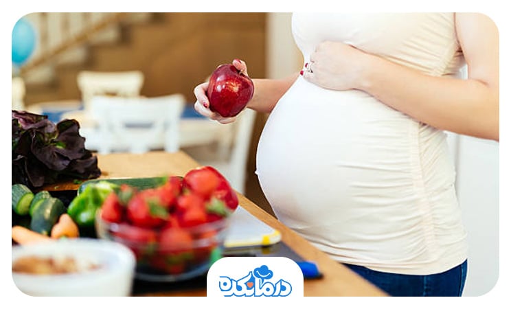 تصویر یک خانم باردار که در حال مصرف سبزیجات است.