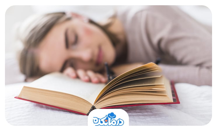 تصویر یک دختر نوجوان که روی کتاب‌هایش به خواب رفته است.