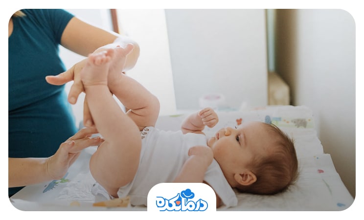تصویر مادری که در حال استفاده از پماد روی پای کودکش است.