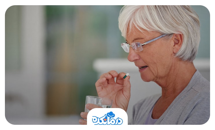 زن سالمندی که در حال خوردن دارو است و یک لیوان آب در دست دارد