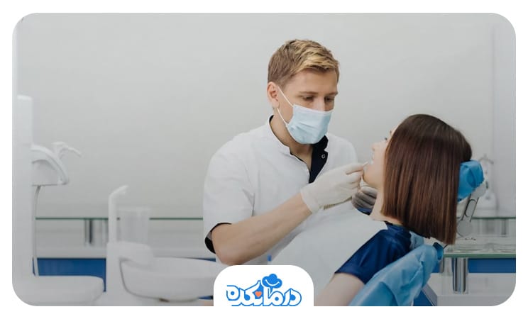 زنی در مطب دندان‌پزشک که پزشک مرد در حال معاینه دندان‌های او است