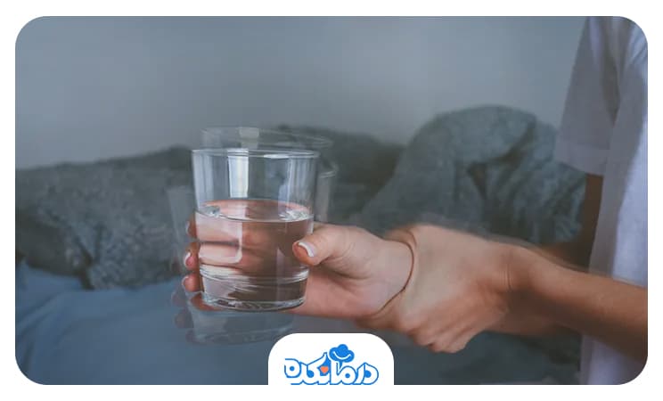 تصویر فردی که به سختی لیوان آب را در دست گرفته است.