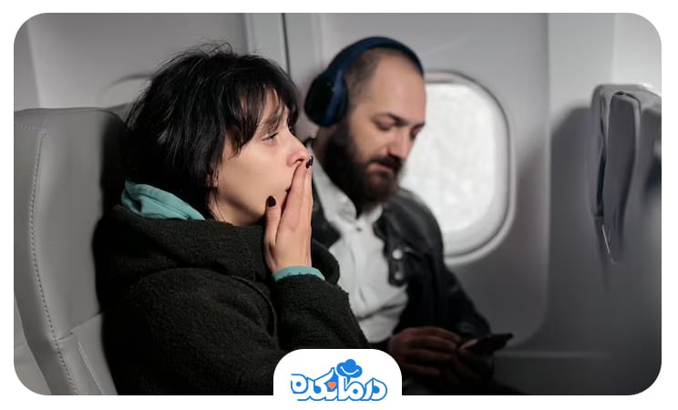 یک مرد و یک زن در داخل هواپیما که مسافر زن علائم پرواز زدگی دارد