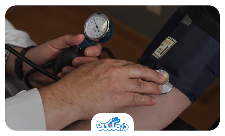 پزشک گوشی پزشکی را روی بازوی بیمار قرار داده است تا فشار خون او را اندازه بگیرد