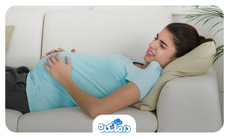 زن بارداری که علائم بارداری را تجربه می‌کند و روی کاناپه دراز کشیده است