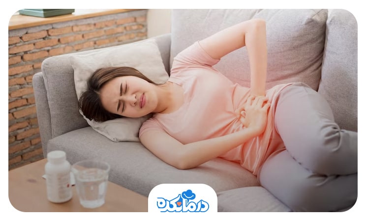 خانمی که روی کاناپه دراز کشیده است و دل درد دارد. شکم درد  می‌تواند از علائم آبسه کبدی باشد.