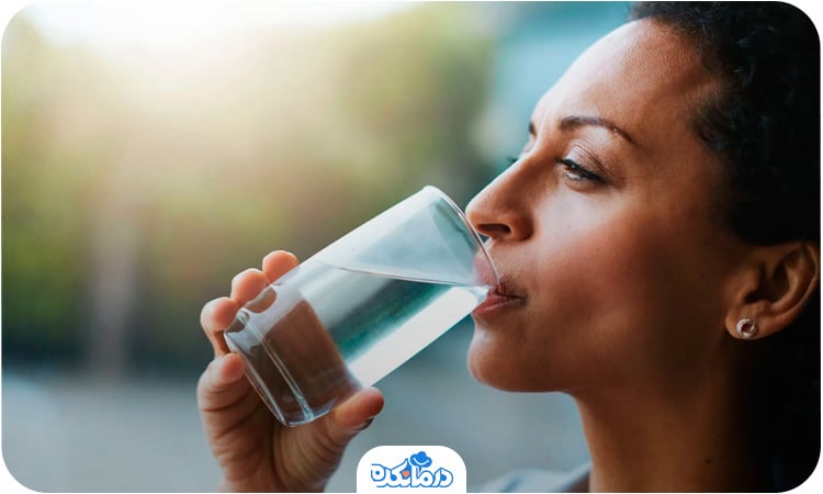 خانمی که در حال نوشیدن آب است. برای درمان خانگی یبوست باید در طی روز به اندازه کافی آب بنوشید.
