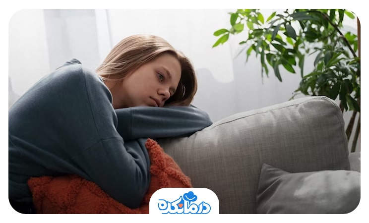 زن مبتلا به افسردگی اساسی که روی مبل نشسته و سر خود را روی پشتی مبل گذاشته است