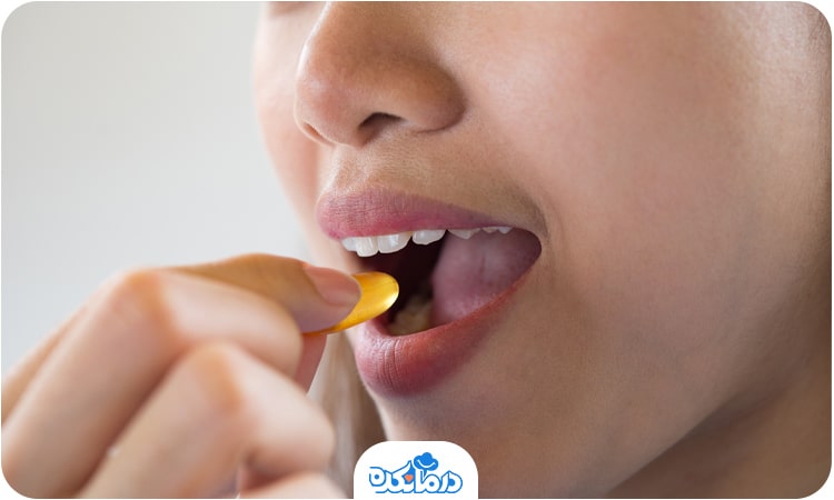 یک زن قرص ویتامین دی را داخل دهان می‌گذارد