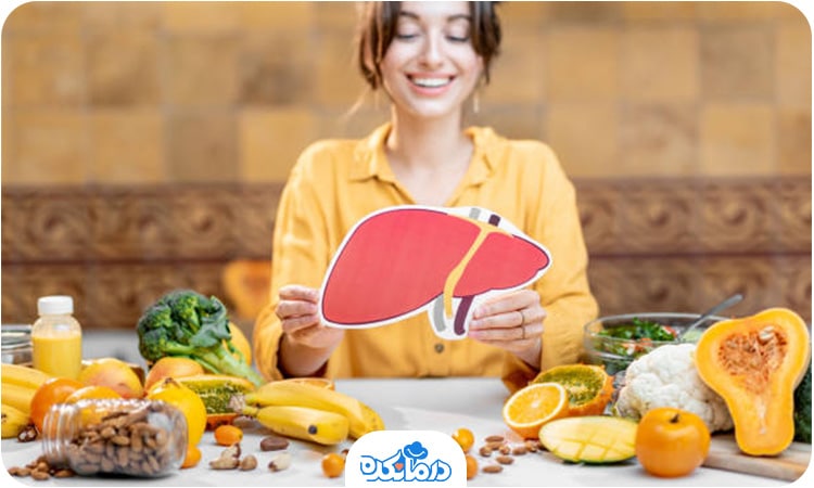 یک خانم عکس کبد را در دست خود گرفته و محصولات غذایی مختلف روی میز قرار دارند.
