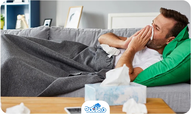 مرد مبتلا به سرماخوردگی که روی کاناپه دراز کشیده و نیاز به قرص سرماخوردگی در بزرگسالان دارد