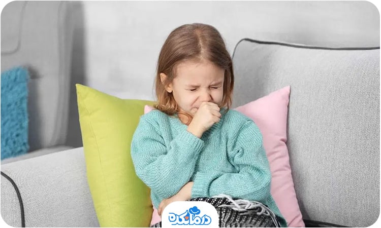 یک دختربچه روی مبل نشسته و در حال سرفه کردن است