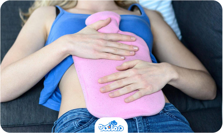تصویر خانمی که دراز کشیده و کیسه آب گرم روی شکمش گذاشته