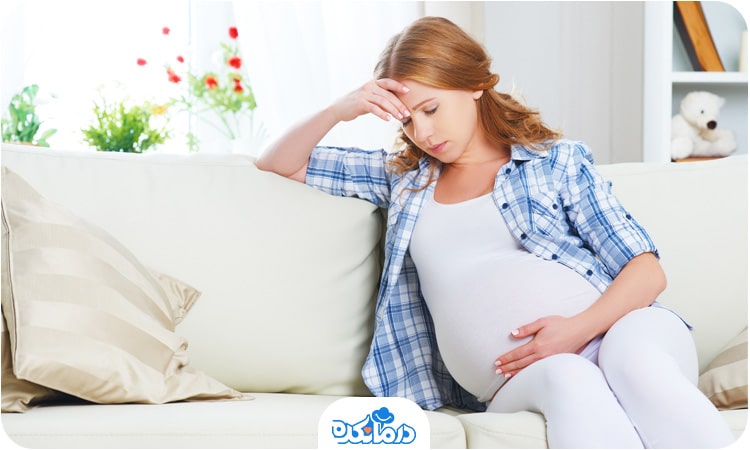 یک زن باردار افسرده که روی مبل نشسته است