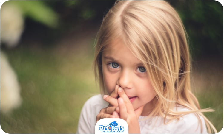 یک دختر خردسال که انگشت‌هایش را جلوی دهان قرار داده است
