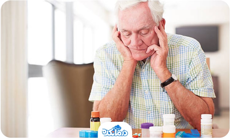 یک مرد سالمند که تعدادی دارو روی میز روبه‌روی او وجود دارد و مرد به آن‌ها نگاه می‌کند