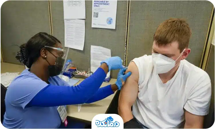 یک مرد جوان که شخصی به بازوی او واکسن تزریق می‌کند