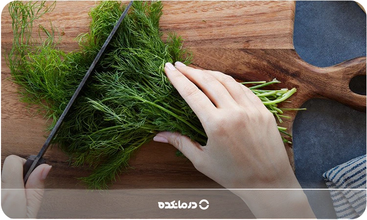تصویر دستی در حال خرد کردن شوید روی تخته