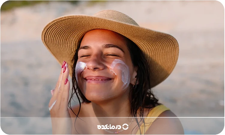 تصویر یک خانم در حال پخش کرم ضد آفتاب روی پوست صورت خود