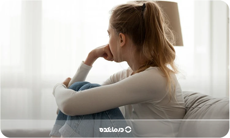  تصویر خانمی که روی مبل نشسته و خیره به گوشه‌ای نگاه می‌کند