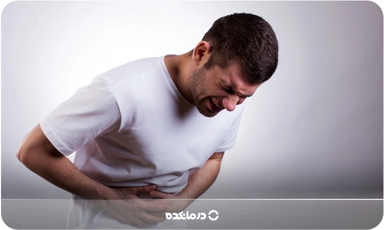 تصویر فردی که دستش روی شکمش است و به دلیل درد خم شده