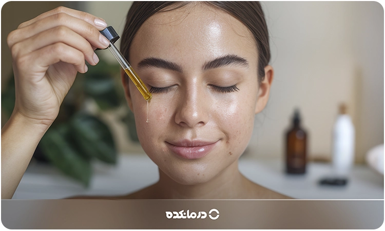 تصویر یک خانم در حال ریختن روغن گیاهی روی پوست صورت خود