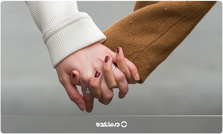 تصویر یک زن و مرد که دست‌هایشان در دست یکدیگر است را می‌بینید