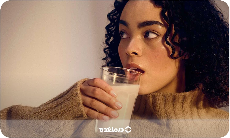 تصویر یک خانم در حال نوشیدن یک لیوان شیر را می بینید