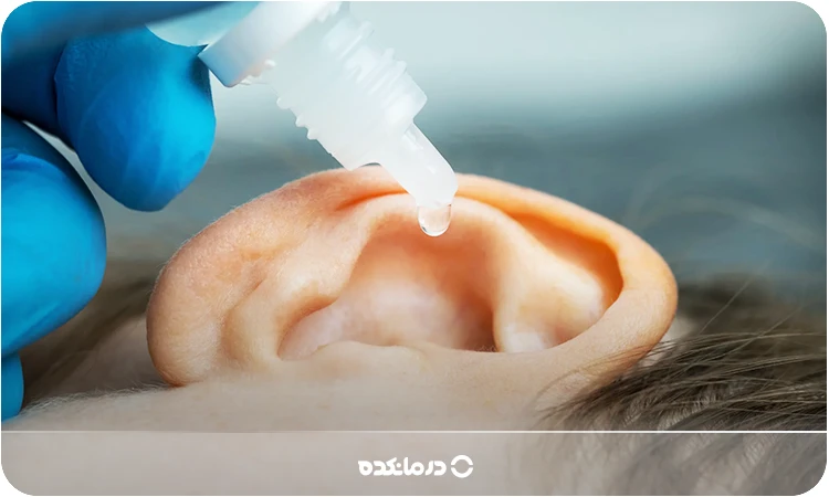 تصویر بیماری که فرد دیگری داخل گوش او قطره می‌ریزد را می بینید