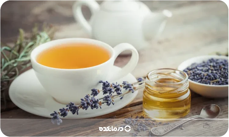 تصویر یک قوری در کنار دمنوش اسطوخودوس را می بینید