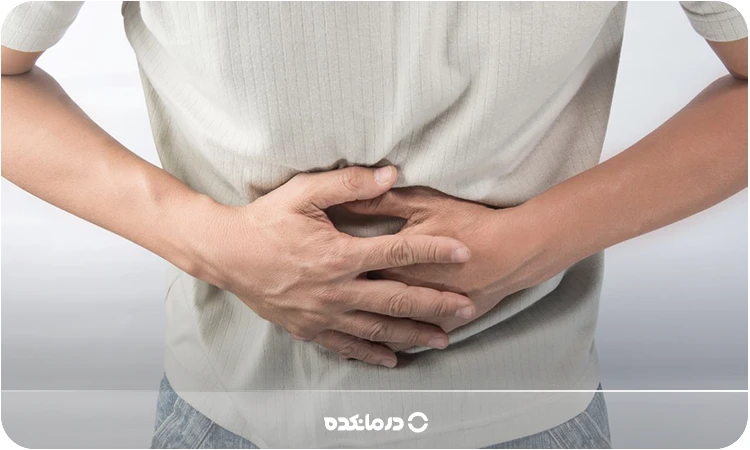 تصویر فردی که به دلیل درد دستش روی شکمش است را میبینید
