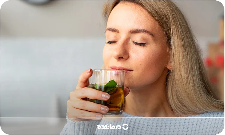 تصویر فردی که در حال نوشیدن دمنوش نعنا است را می بینید