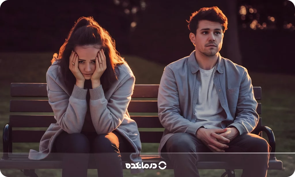 تصویر زن و مردی که روی نیکمت نشسته‌اند را می بینید. زن ناراحت است و دست‌هایش روی صورت گذاشته است.