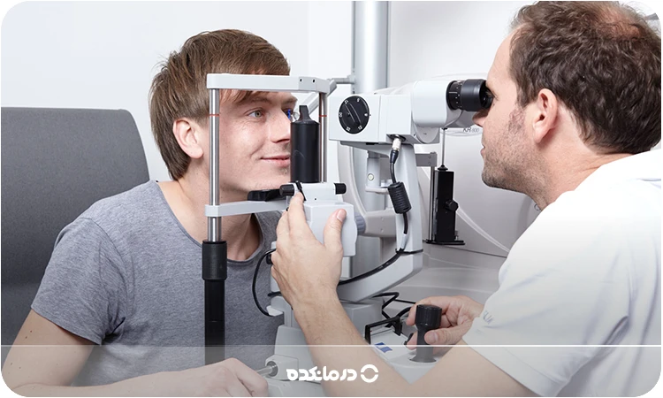تصویر چشمپزشک در حال معاینه چشم یک آقا با دستگاه مخصوص