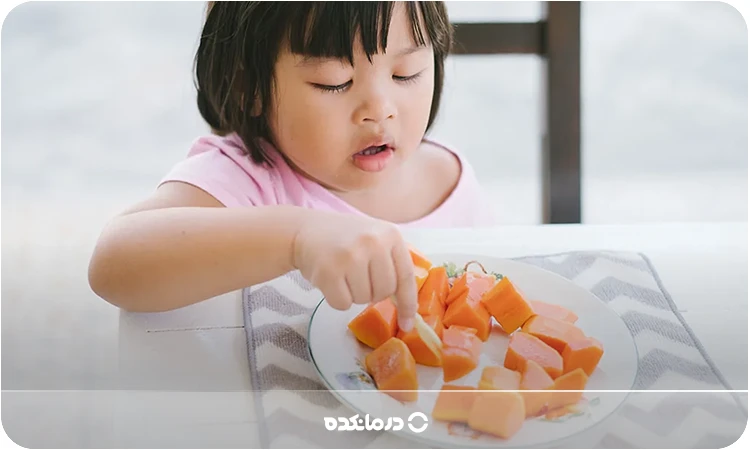 تصویر کودکی که در حال خوردن پاپایا است را می بینید