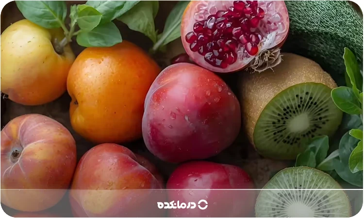 تصویر میزی پر از میوه‌های انار، سیب، کیوی و آلبالو را می بینید