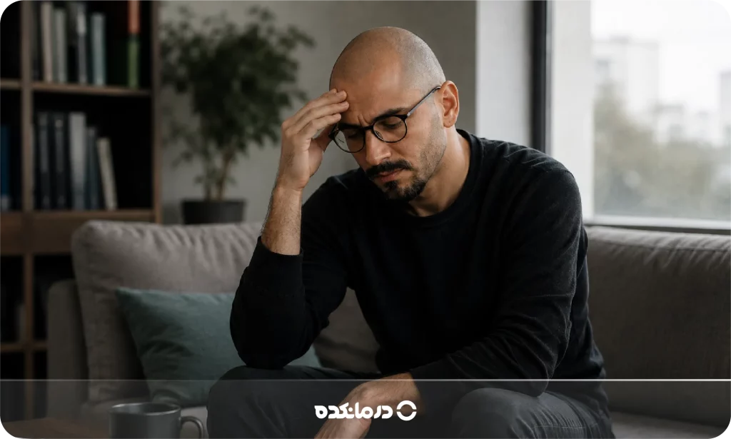 تصویر فردی که با حالت اضطراب دستش را روی پیشانی‌اش گذاشته را می بینید