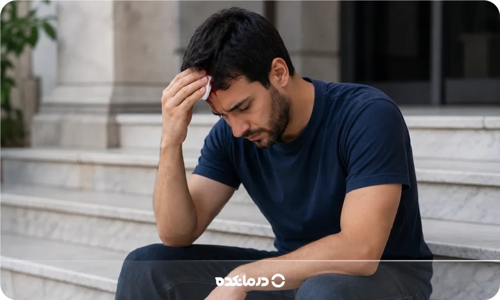 تصویر فردی که سرش آسیب دیده و نشسته است را می بینید