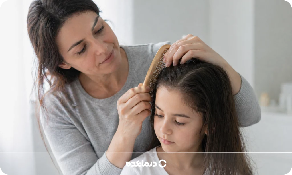 تصویر یک مادر در حال شانه زدن موهای کودک را می بینید
