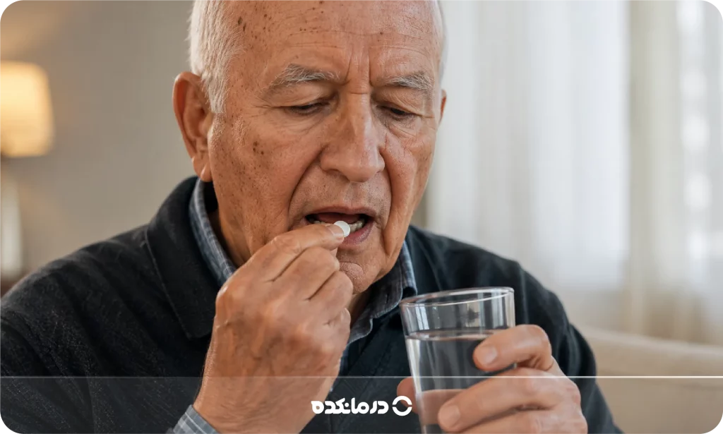 تصویر فرد مسن در حال خوردن قرص و یک لیوان آب را می بینید