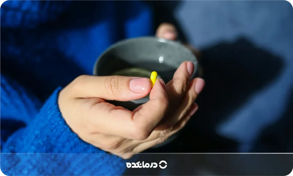 تصویر یک زن جوان در حال خوردن قرص را می بینید